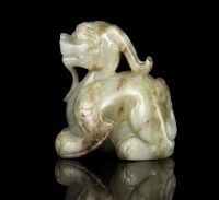 MING DYNASTY A CELADON AND RUSSET JADE CARVING OF A MYTHICAL BEAST